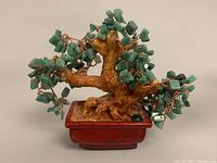 Close up of a small green jade chip bonsai money tree with wired branches and a brown ceramic pot