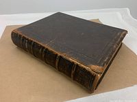 Front cover of the antique leather bound Holy Bible showing wear and corner scuffing