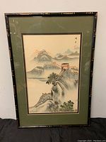 Full view of the framed painting showing the Great Wall of China with mountainous landscape and green matting.
