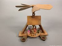 Front view of the wooden nativity carousel showing the rotating platform with figures and propeller on top.