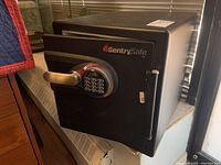 Black SentrySafe BG-73802 security safe closed with keypad lock, showing handle and logo on front.