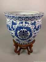 Front view of the blue and white porcelain planter on wooden base showing detailed pattern and circular motifs.