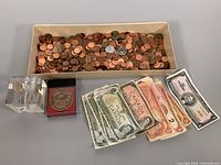 Wide view showing box of assorted pennies, stacked Canadian and American banknotes, and a few collectible coins.