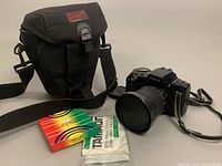 Photo showing Canon EOS-10s camera with Tamron lens mounted, carrying bag, optical filter, and Tamron lens manuals.