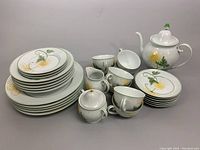 Photo showing entire chinaware set with teapot, creamer, sugar bowl, plates, teacups, and saucers grouped for display.