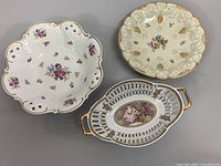 Three vintage hand-painted serving bowls displayed together on a gray surface.