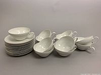 Stack of white teacups and saucers showing condition and quantity of pieces