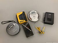 Overview of the audio devices including Sony CD Walkman, Sony Sports radio cassette player, Sanyo CD player with yellow earbuds, Toshiba cassette player
