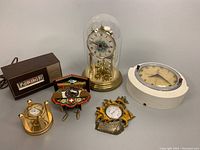 All six vintage clocks and thermometers displayed together on table for overview.
