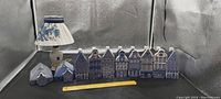 Full set of 10 Delft blue ceramic houses with one matching Delft blue floral pattern lamp, ruler for scale.