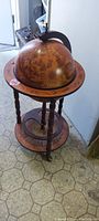 Full view of closed wooden Italian globe bar showing detailed antique-style map design on the globe and base shelf.