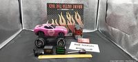 Lot contents including pink remote control car, remote controller, battery pack, power pack, tool, manual, and box with flame graphics.