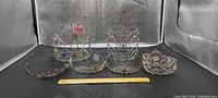 Photo shows six tiaras of differing heights and designs arranged in a display with a ruler for scale.
