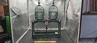 Full front view of vintage wooden bird cage showing two dome-shaped tops with finials and rectangular base with wire bars.