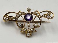 Front view of brooch showing amethyst and seed pearls in scroll design