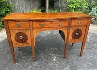 Full front view of sideboard showing bow-front top, three drawers and two cabinet compartments with inlay detail