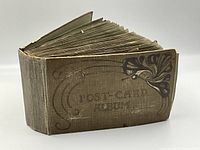 Side view of the antique post-card album showing wear and thickness.