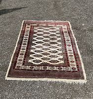 Full view of the rectangular area rug with diamond-like geometric pattern and multiple decorative borders in deep red, brown, and cream colors.