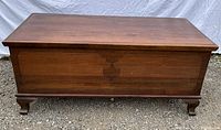 Front view of cedar chest showing carved shell motif and bracket feet