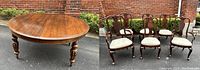 Mahogany oval dining table with carved turned legs and six matching upholstered chairs displayed together.