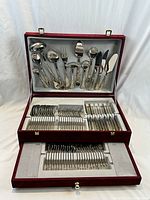 Full view of the service set inside the open original burgundy box showing upper and middle compartments with serving utensils and cutlery.
