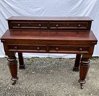 Front view of the desk showing two-tier belt drawers and turned front legs on casters