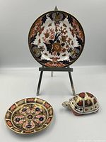 Group view of the two plates and the turtle paperweight showing ornate patterns and sizes