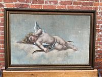 Full view of framed pastel painting of cherub against brick background