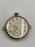 Front view showing white enamel dial, blue numerals and gold hands