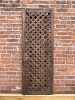 Full front view of carved wooden privacy screen panel against brick backdrop