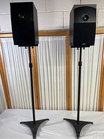 Photo of the pair of speakers mounted on adjustable black stands showing overall size and shape