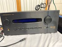 Front view of B&K Components AVR 507 receiver showing overall design, control buttons, display, and knobs with attached power cord.