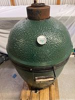 Full front view of green ceramic kamado grill on wooden pallet