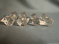 Four crystal cutting tool holders arranged on a blue surface, showing their shapes and faceted crystal design.