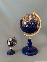 Both globes together showing size difference, blue bases and brass mounts, spinning action