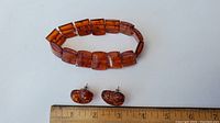 Amber bracelet and heart-shaped amber stud earrings placed next to a ruler for size reference.