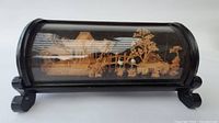Front side view of the carved wooden Chinese landscape inside a black wooden and glass display case.