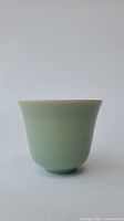 Front view of the green celadon cup showing its smooth surface and slightly flared rim.