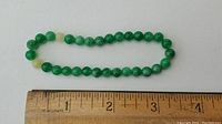 Top view of the jade bead bracelet with a ruler for size reference showing about 7 inches in circumference.