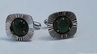Front view showing textured square silver-tone frames with centrally set polished oval green jade stones on cuff links.