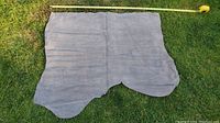 Irregularly shaped large grey suede or nubuck leather piece laid flat on grass with measuring tape showing width approximately 45 inches.