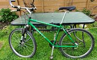 Green Norco Berretta mountain bike side view showing the full frame, wheels, and seat