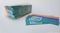 Large bundle of sealed stamp sheets with colorful gradient background and a single stamp on each sheet.