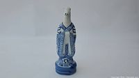 Front view of blue and white porcelain snake figurine with detailed robe pattern and base