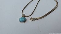Full view of sterling silver pendant with blue stone and attached chain showing overall appearance.