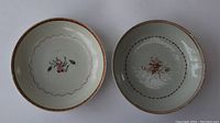 Top view of two Chinese Export porcelain plates showing central floral motifs and different colored rims.