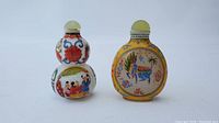 Front and side views of two Chinese snuff bottles, one gourd-shaped with painted human figures and characters, the other round with a yellow background and landscape motifs.