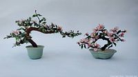 Full view of both jade trees showing size difference and floral designs in celadon pots