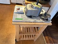 Photo of Cuisinart food processor components and user manual on top of rolling kitchen cart with marble top.