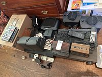 Wide shot of Marantz SR-52 stereo receiver with several wires and electronic accessories including radios and alarm clocks, plus a box of music CDs.